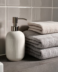 white ceramic soap dispenser and towels, modern bathroom detail