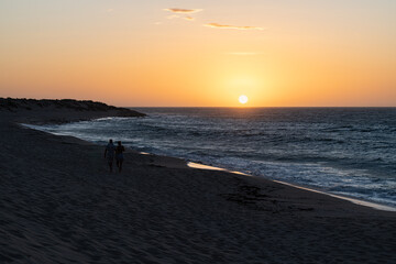 Couple (unrecognizable) walking along a beach at sunset in Cape Range National Park, Western...