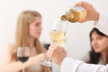Woman pouring exquisite wine from bottle into glass on light background
