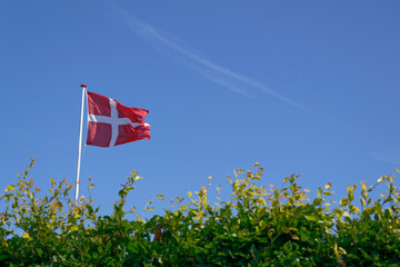 The Danish flag Dannebrog blows in the wind against a blue sky