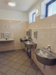 public toilet with stainless steel sinks and a changing table for the baby in car park highway