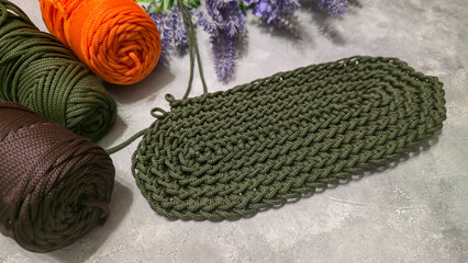 Crochet bag bottom made of green polyester cord. On a gray background. design