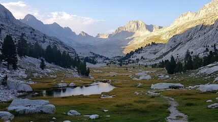 Serene mountain valley at sunset, featuring a tranquil lake, grassy meadows, and rugged peaks.  Golden hour light bathes the landscape