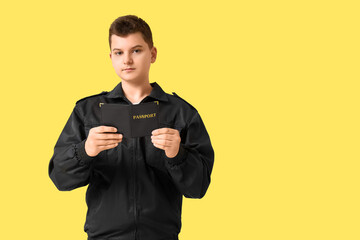 Teenage police officer with passport on yellow background
