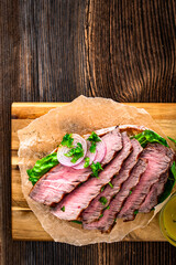 Takeaway sandwich with slices of grilled beef steak on wooden table	