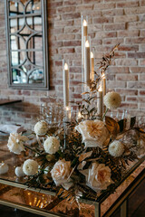 Elegant candlelit floral arrangement on glass table with soft lighting