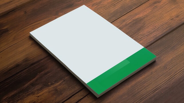 Blank white notepad with a green stripe on a wooden table, ideal for mockups and presentations.