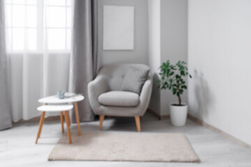 Interior of light living room with grey armchair and tables