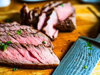 Slices of grilled beef steak on wooden cutting board