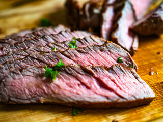 Slices of grilled beef steak on wooden cutting board