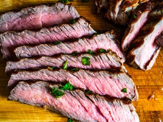 Slices of grilled beef steak on wooden cutting board
