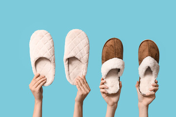 Female hands holding slippers on blue background