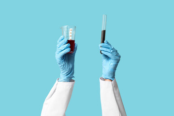 Scientist's hands holding test tubes with soil and red liquid on blue background