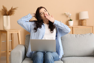 Tired young woman using laptop and  yawning at home