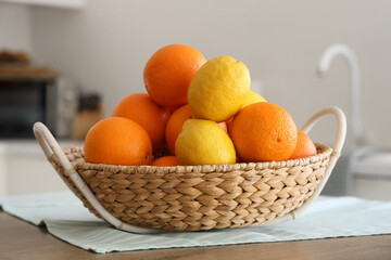 Wicker basket with citruses on table in white kitchen