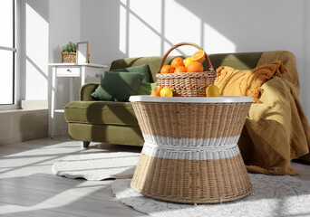 Wicker basket with citruses on coffee table near sofa in living room