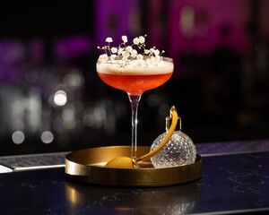 blush-toned cocktail with a frothy top is elegantly garnished with delicate white baby's breath...
