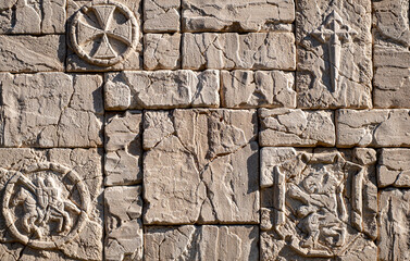 A close-up shot of a textured stone wall made of rectangular bricks, giving it a rugged, worn-out...