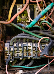 a cluttered, intricate network of colorful electrical wires and cables, predominantly green, pink,...