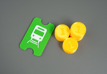 A public transport ticket and a stack of coins. A metro, tram or train ticket.