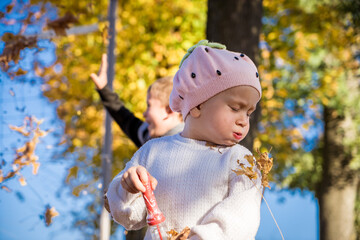 Adorable preschooler girl enjoying nice and sunny autumn day outdoors. Happy child sitting on the...