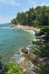 A beautiful coastal scene featuring clear turquoise waters, rocky shores, and lush green trees under a bright sky.