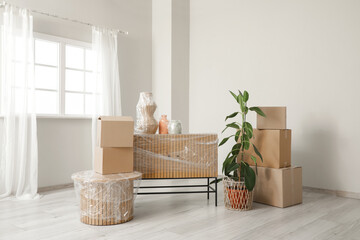 Wrapped things with stretch film, plant and boxes in room on moving day