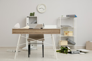 Interior of light office with messy workspace and scattered belongings after earthquake
