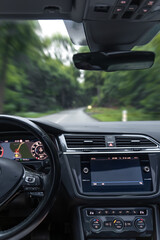 Vertical photo inside car. Forest road in motion. Speed and navigation.