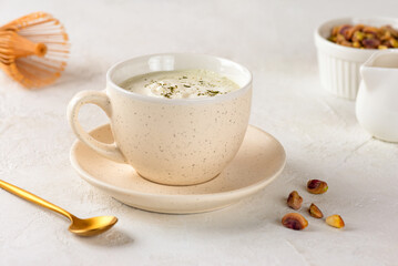 Pistachio green matcha latte tea in a cup on a white table. Healthy drink, vegan.