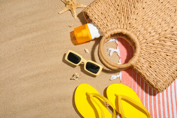 Composition with bottle of sunscreen cream, seashells and beach accessories on sand as background,...