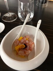 Raw red shrimp tartare served with mango cubes and edible flower in a white ceramic bowl, fine dining Japanese fusion appetizer in an upscale restaurant with elegant minimalist presentation style