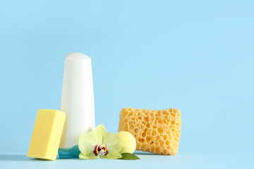 Composition with bottle of shower gel, soap bar and bath sponge on blue background, closeup