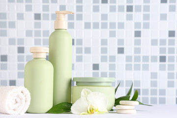 Composition with bottles of shower gel, spa stones and towel on table near blue tile wall, closeup
