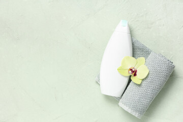 Composition with bottle of shower gel, orchid flower and towel on green grunge background