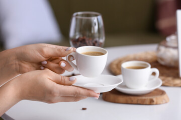 Female hands with cup of hot coffee at home