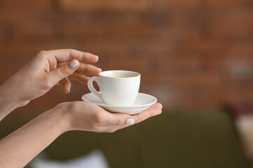 Female hands with cup of hot coffee at home
