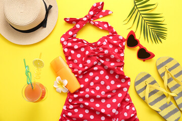 Bottle of sunscreen cream, swimsuit and beach accessories  on yellow background