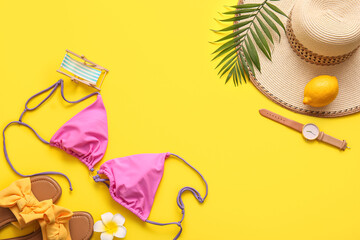 Summer composition with swimsuit, lemon and beach accessories on yellow background