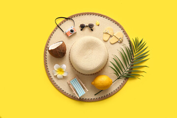 Summer composition with coconut, lemon and beach accessories on yellow background