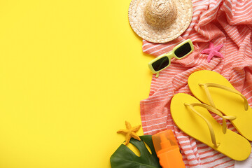 Summer composition with beach towel and accessories on yellow background