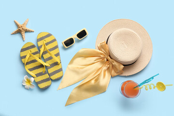 Summer composition with glass of cocktail and beach accessories on blue background