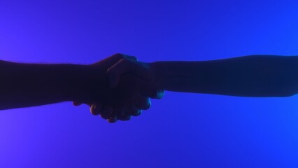Silhouette of Hands Shaking Against Blue and Purple Background