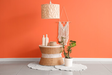 Table and houseplant near orange wall in interior of living room