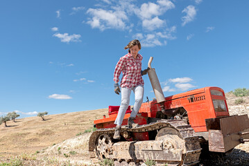 Under the countryside sun, a woman getting off her old tractor