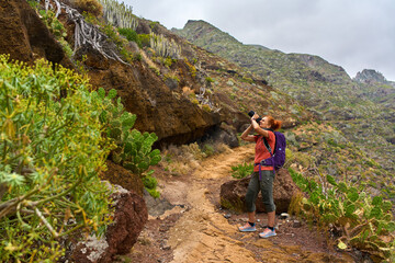 Woman photographing on volcanic trail