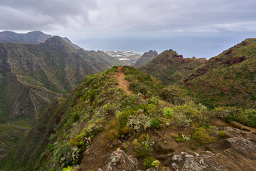 Volcanic trail under rugged cliff