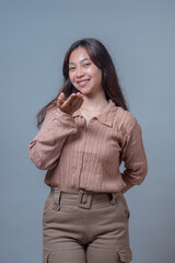 An Indonesian woman smiling playfully while blowing a kiss. Her warm expression and body language...