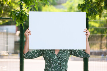 Young woman holding blank poster on stadium