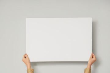Female hands holding blank poster on white background